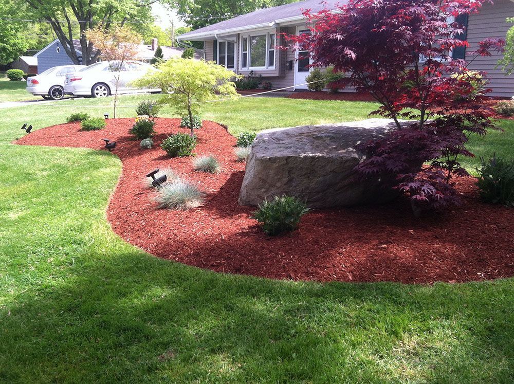 A rock sitting in the middle of a green lawn.