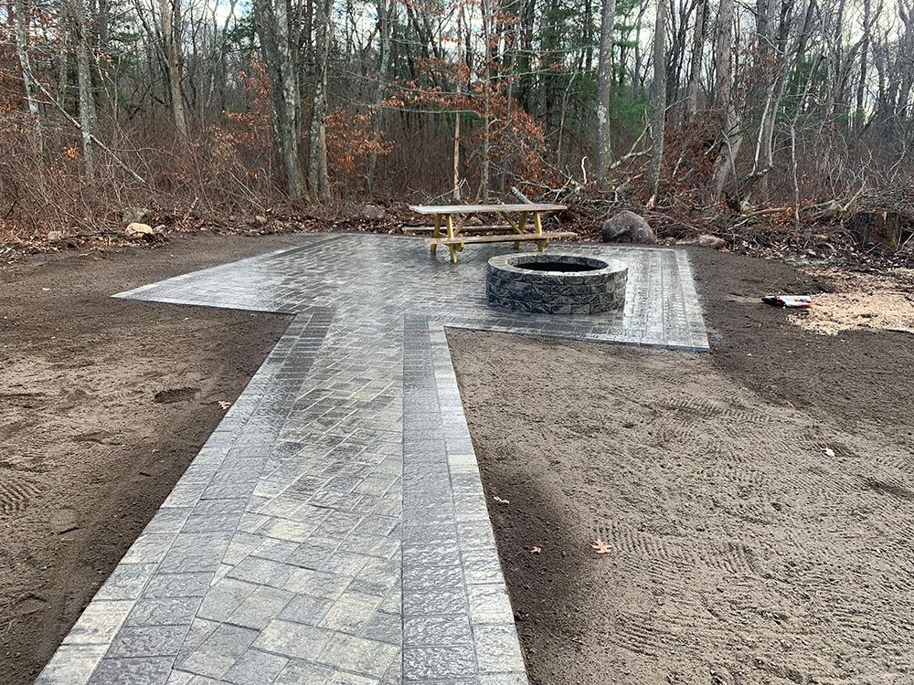 A cozy patio with a fire pit and a picnic table.