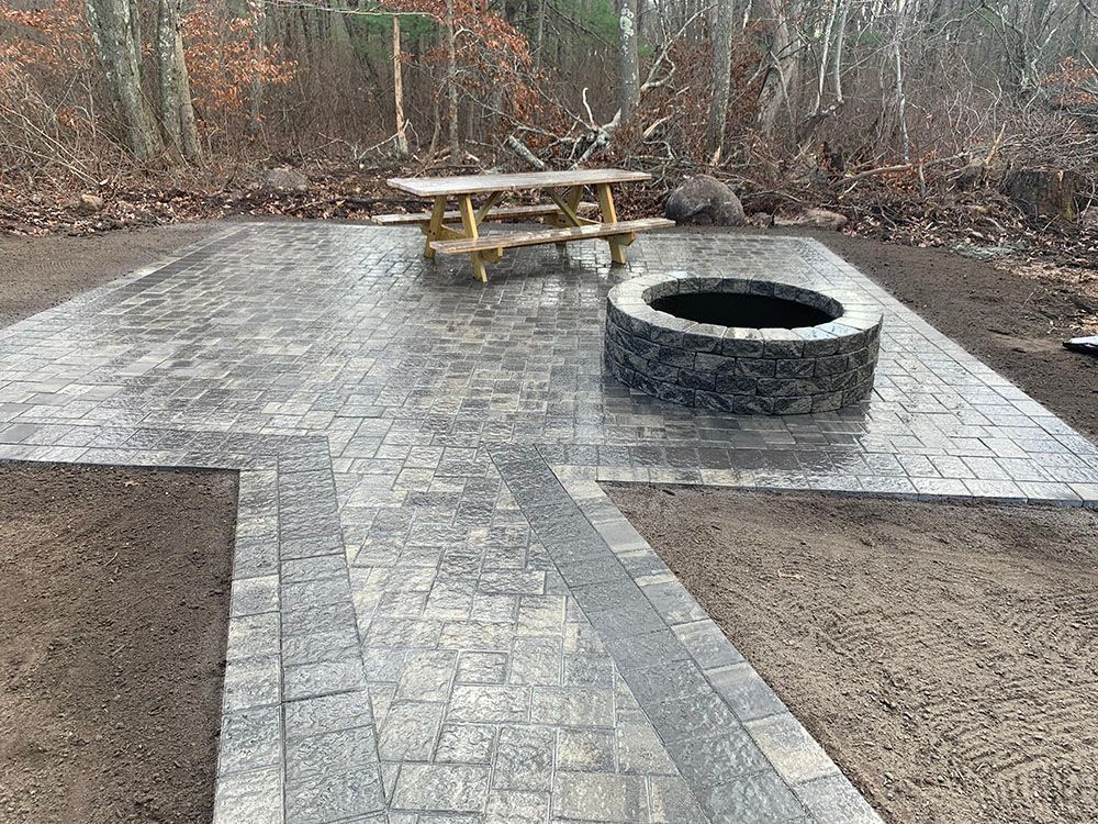 A cozy patio with a fire pit and a picnic table, perfect for outdoor gatherings and relaxation.