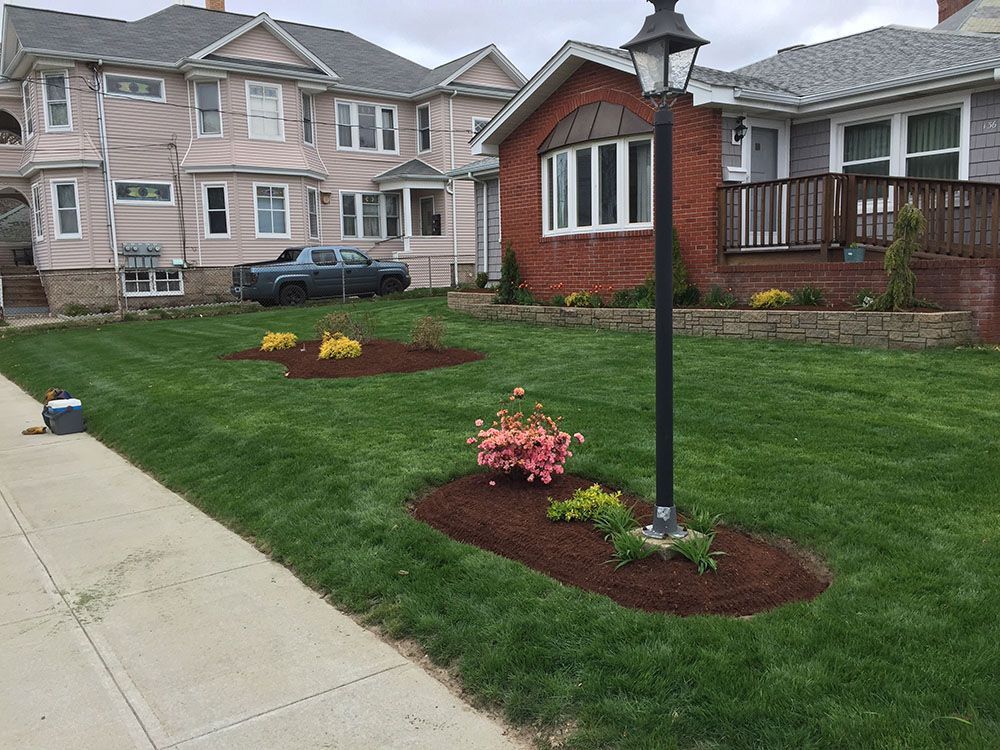 A well-maintained lawn with a beautiful garden in front of a house.