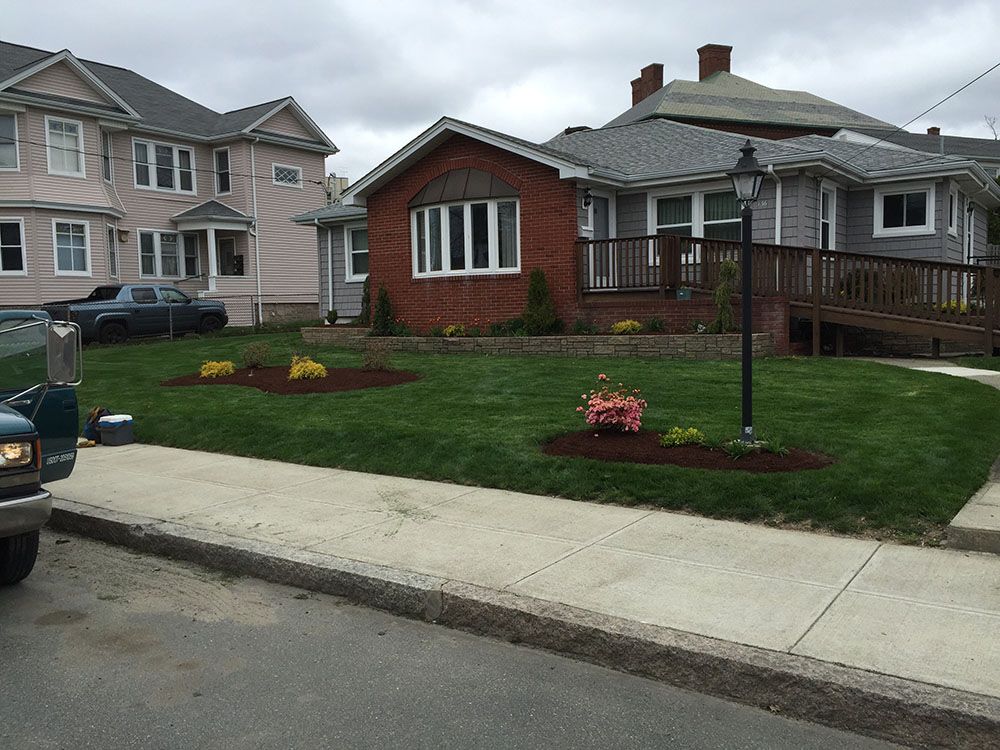 A well-maintained lawn with a garden in front of a house.