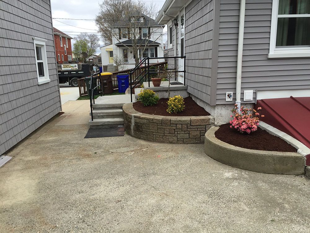 A colorful flower bed with a bench in front of a charming house, creating a serene and inviting atmosphere.