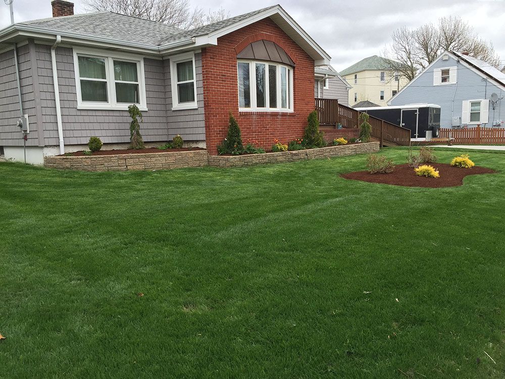 A well-maintained lawn with a charming garden in front of a house, adding beauty to the overall landscape.