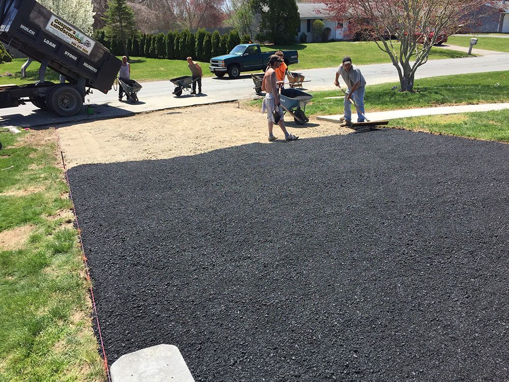 Several men in work attire repairing a driveway with shovels and tools.