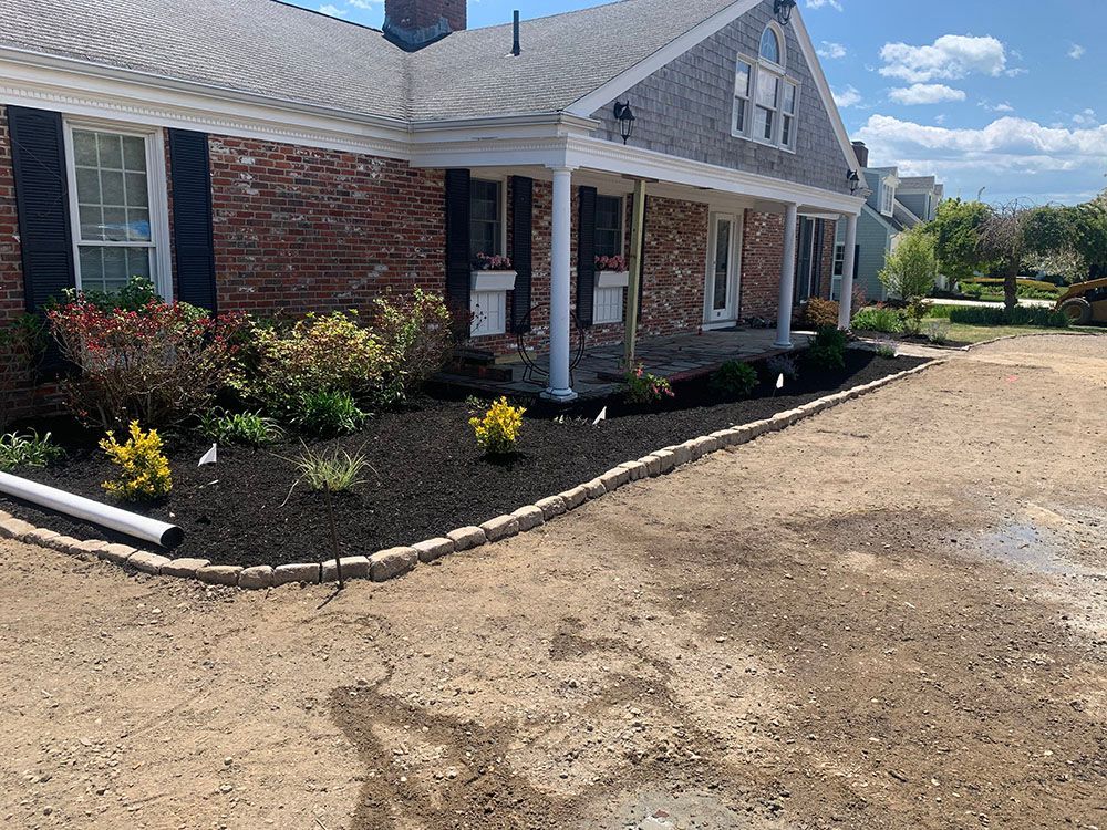 Driveway with black mulch bed and landscaping.