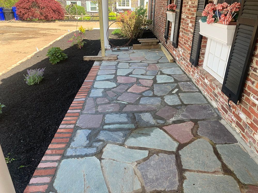 A stone walkway lined with a brick path and adorned with flower pots.
