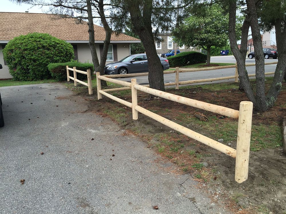 Wooden fence beside a car in a rural setting.