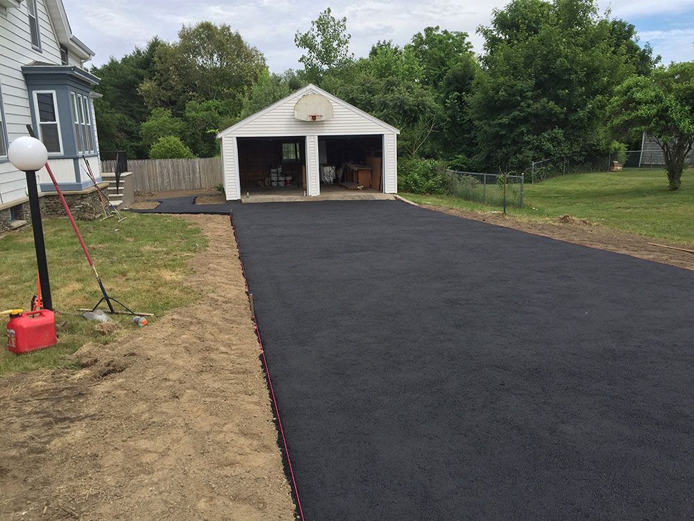 A black asphalt driveway leading to the garage, providing a smooth and durable surface for vehicles.