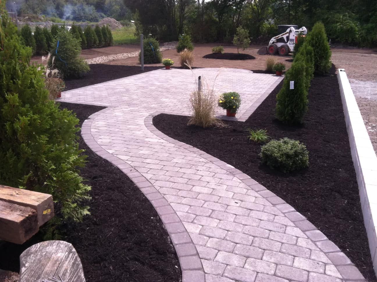 a brick walkway in a garden with trees and bushes