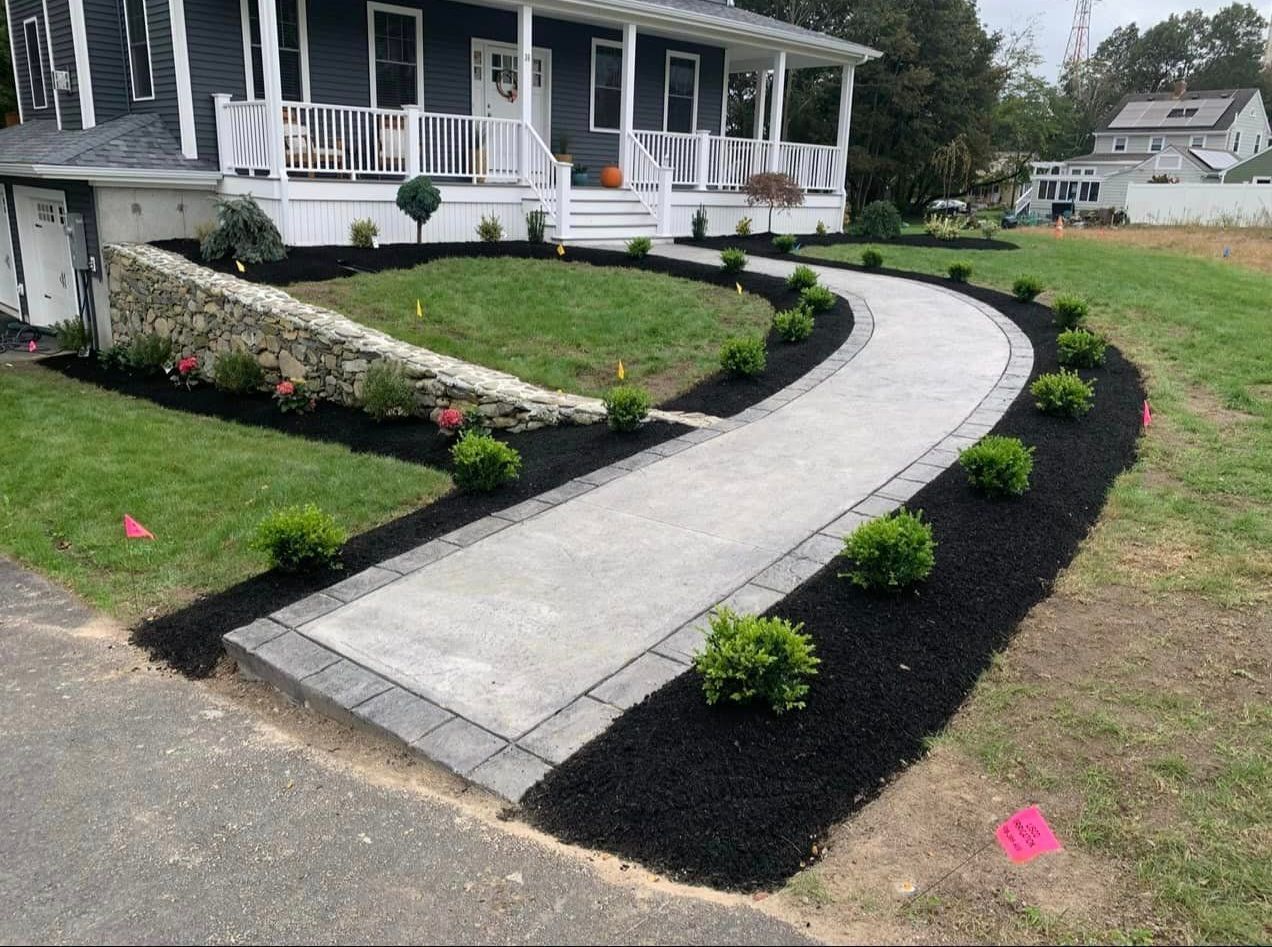 a concrete walkway is leading to a house with a large porch