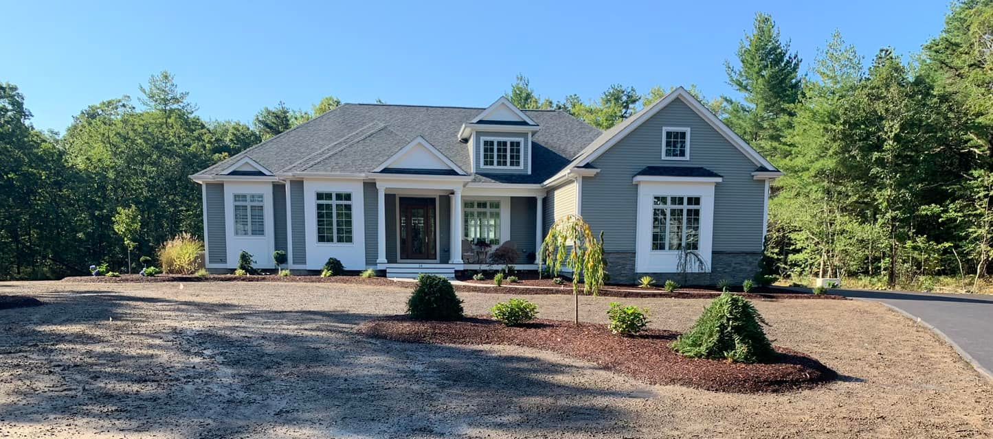 a large house is sitting on top of a dirt field surrounded by trees
