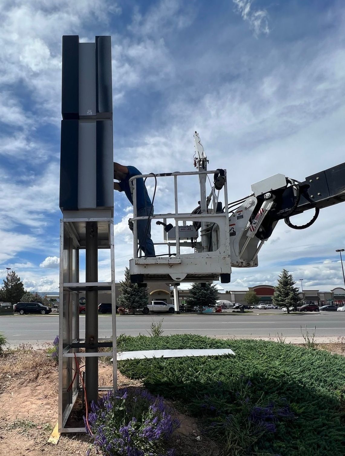 A man in a bucket is working on a sign