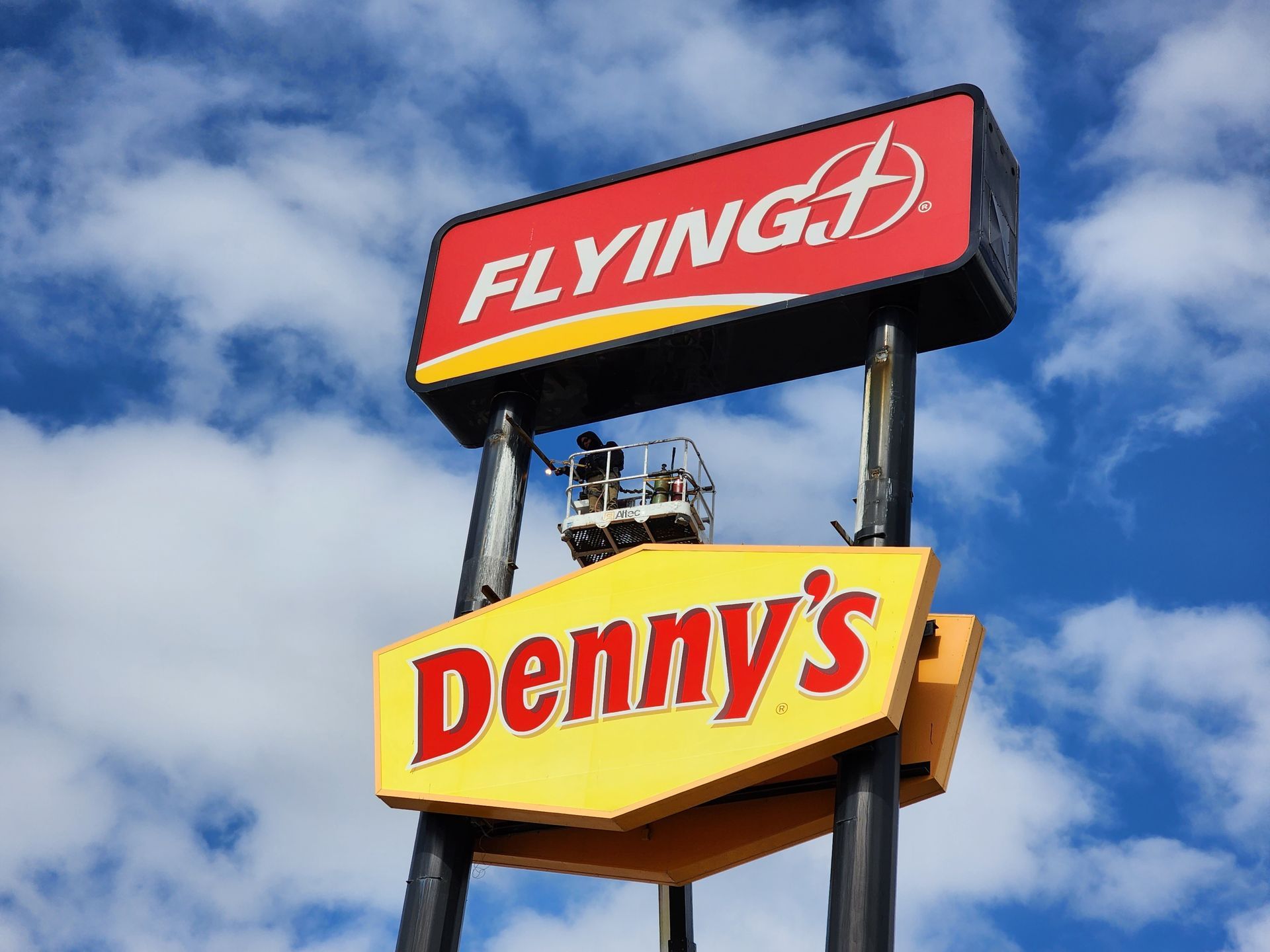 A flying denny 's sign with a blue sky in the background