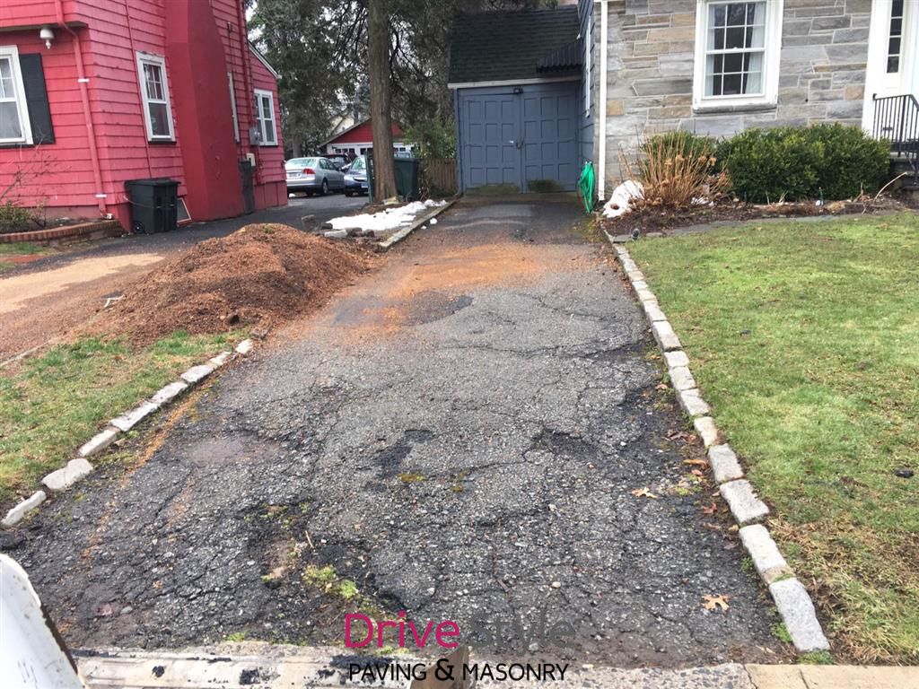 Gravel driveway beside red and white houses, leading to a garage