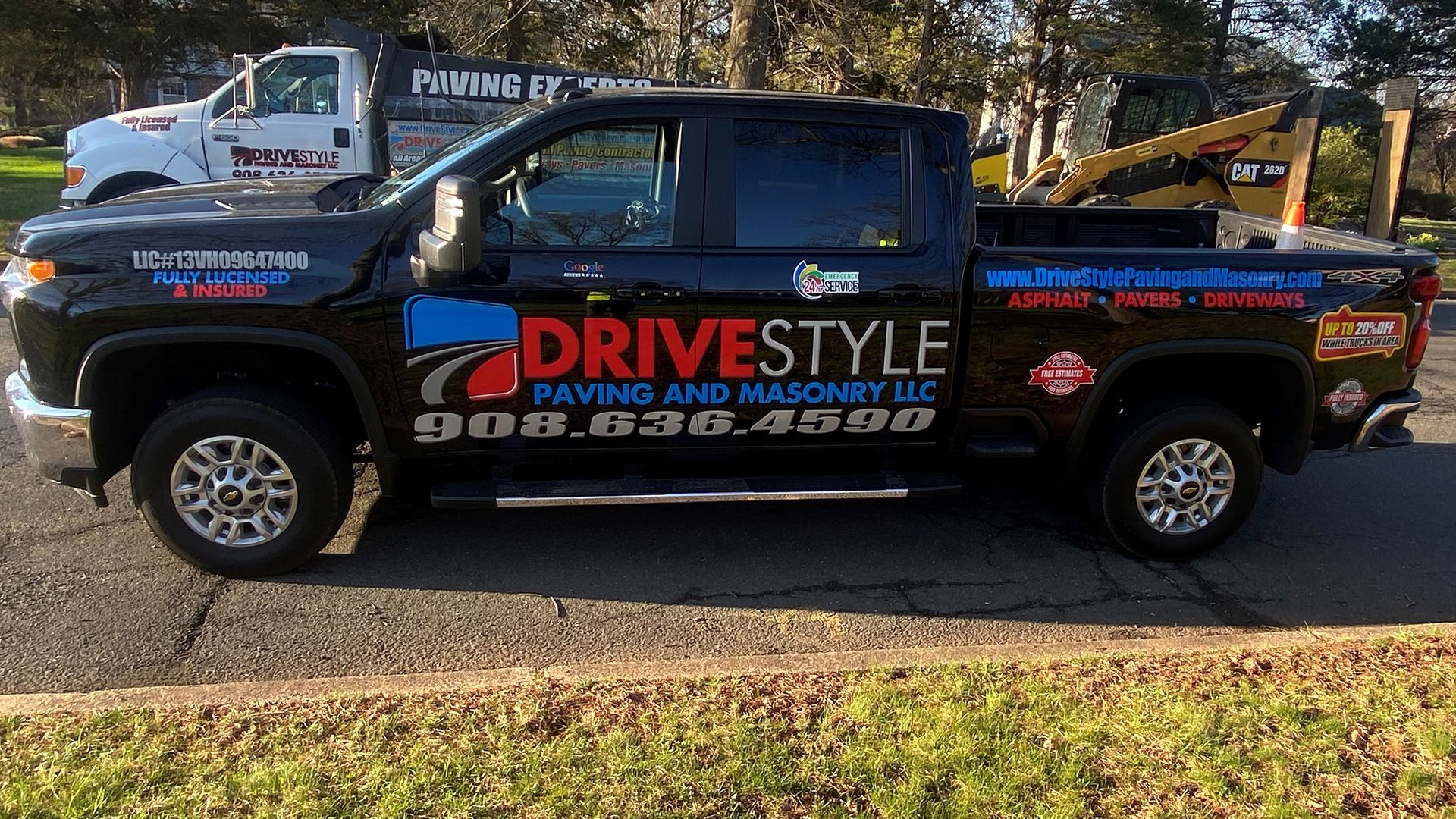 Black pickup truck with DRIVESTYLE paving and landscaping logo parked on a grassy roadside.