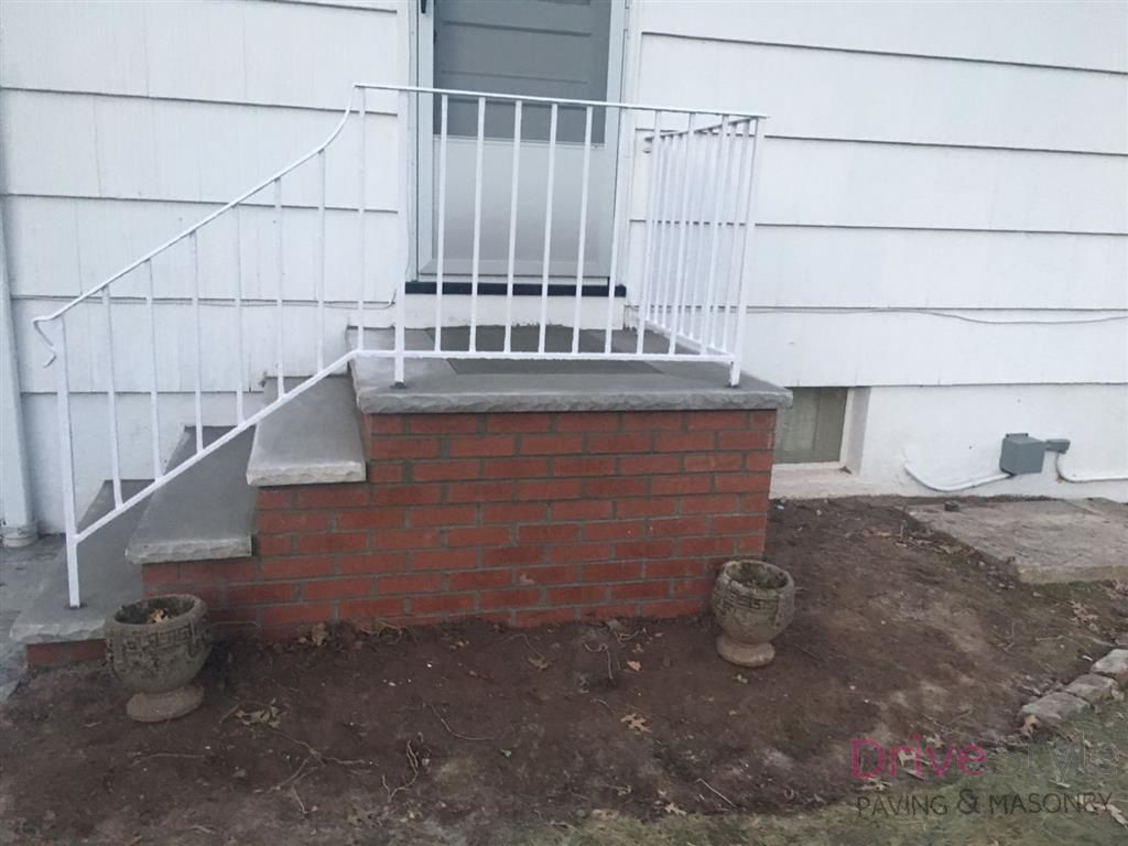 Brick front steps with white railings leading to a house entrance