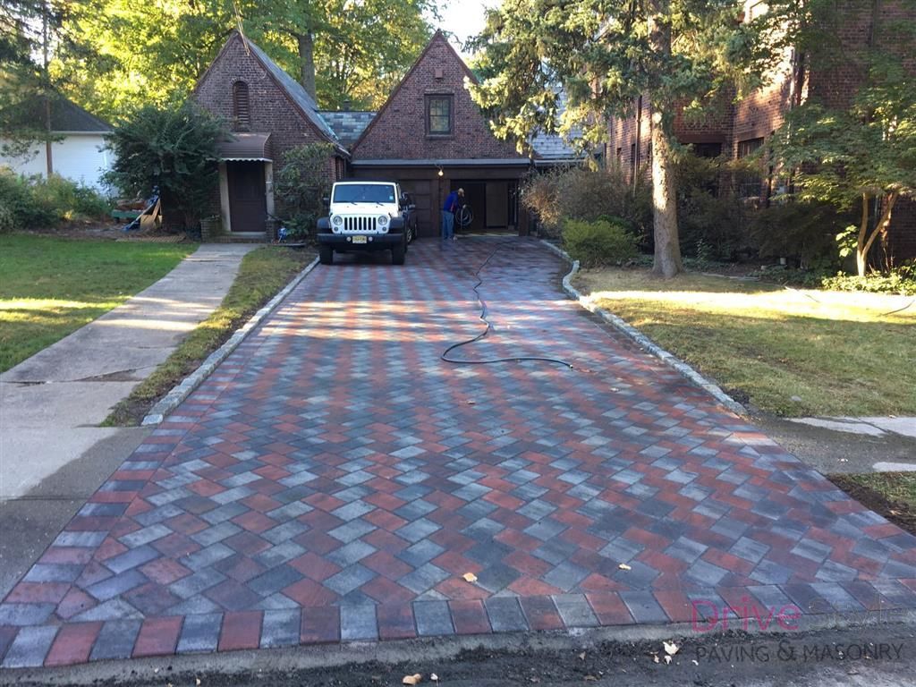 Brick driveway leading to a house with a white golf cart parked in front of the garage.