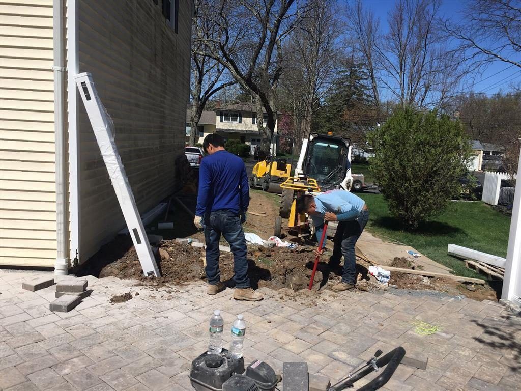 Workers digging beside a house during a backyard construction project