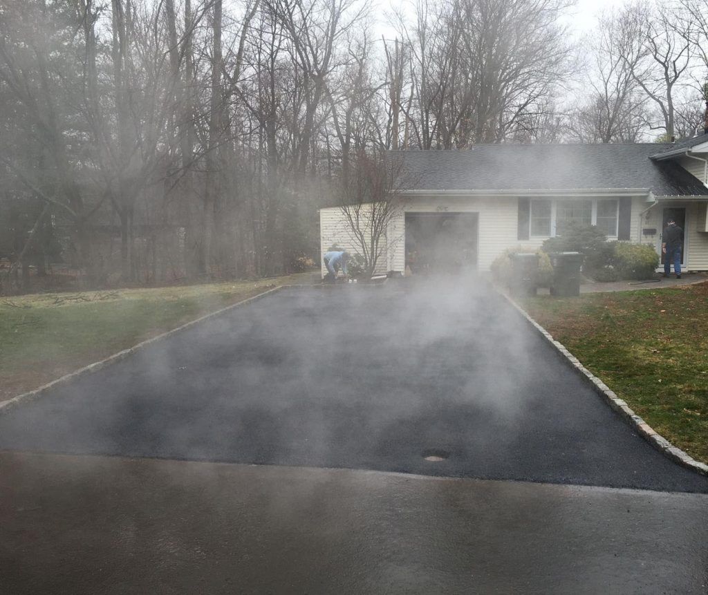 Steaming driveway beside a house on a foggy, overcast day