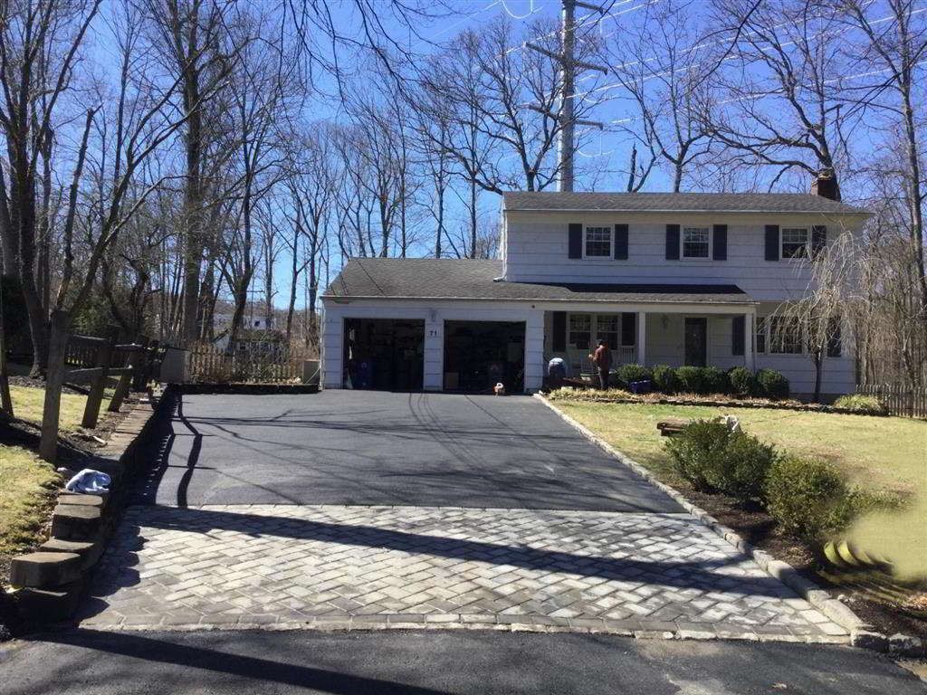 Suburban house with two-car garage and steep driveway, viewed from the street on a sunny day