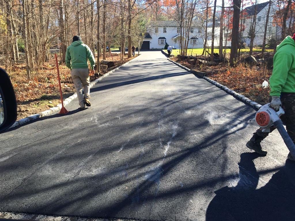 Workers walking on a newly paved road through a wooded neighborhood