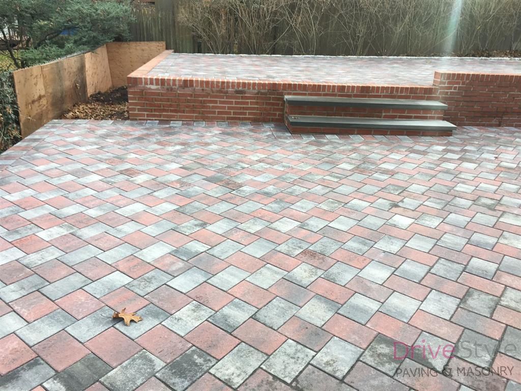 Brick patio with a raised step and bench in a fenced outdoor area