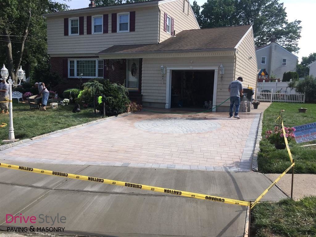 New driveway being installed at a suburban house, with workers and yellow caution tape.