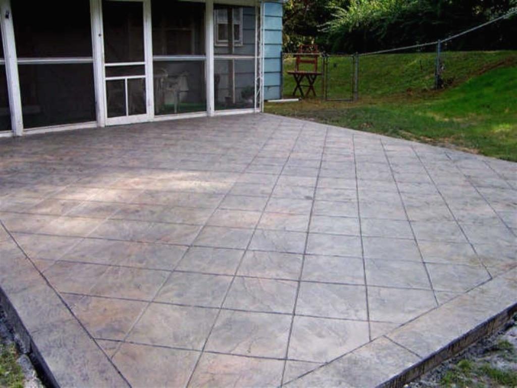 Patio with large light-gray tiled pavers beside a house and grassy yard