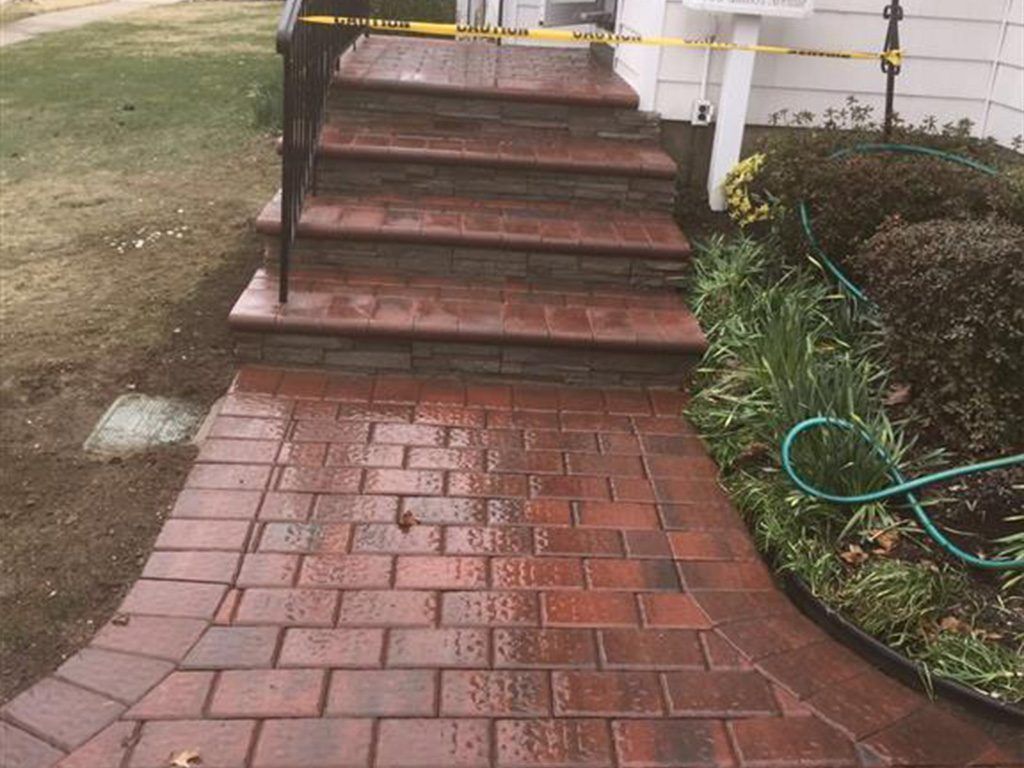 Brick walkway leading to a front porch with steps, cordoned off with yellow caution tape.
