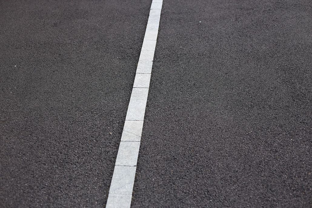 Close-up of dark asphalt road with a white center line.