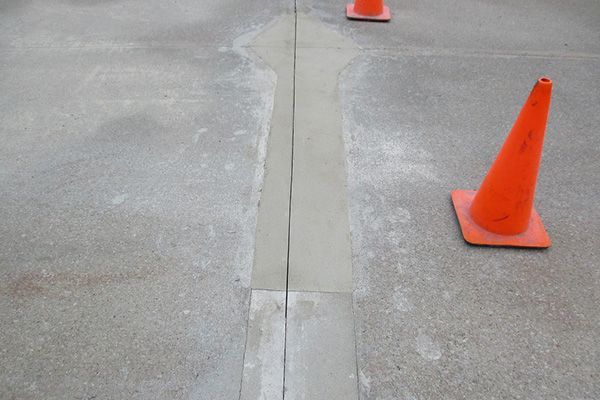 Orange traffic cones marking a cracked concrete seam