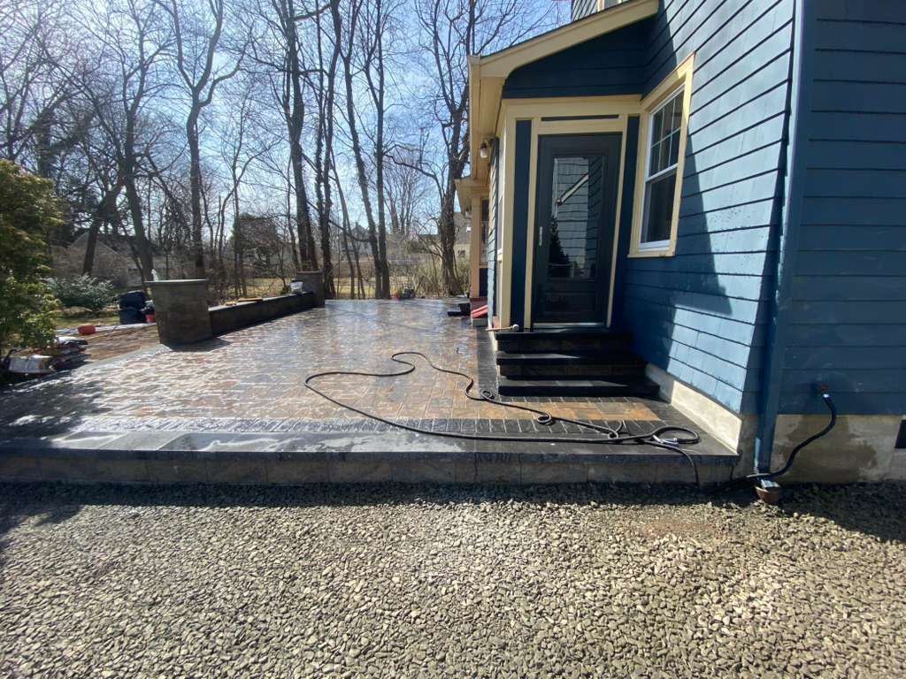 Blue house entry with steps and ramp beside a gravel driveway, surrounded by bare trees