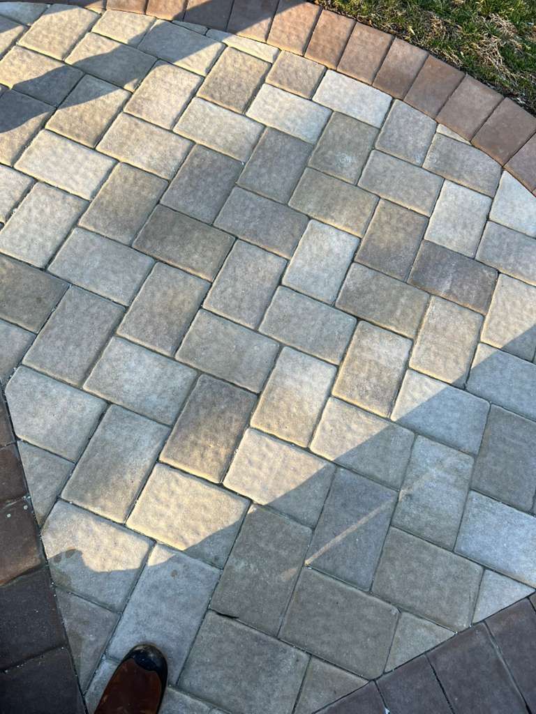 Sunlit curved stone paver walkway with a shoe at the bottom edge
