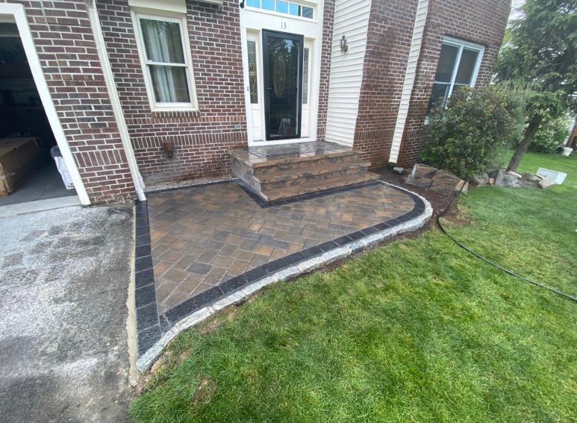 Brick house entry with curved stone walkway and walkway edging beside green lawn