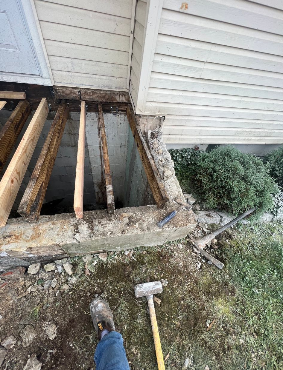 Collapsed porch floor with exposed joists and debris beside a house exterior