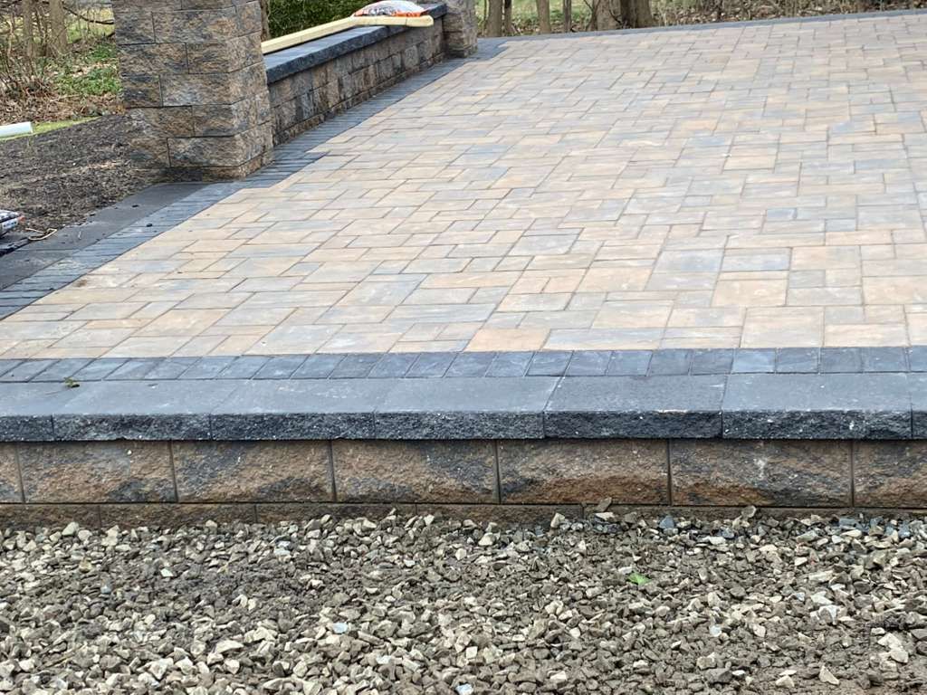 Stone-paved patio with a low stone border and gravel in the foreground