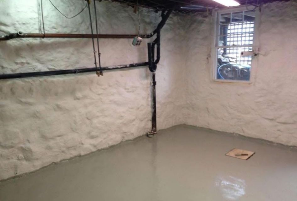 Small unfinished basement room with white walls, exposed pipes, a window, and a concrete floor.