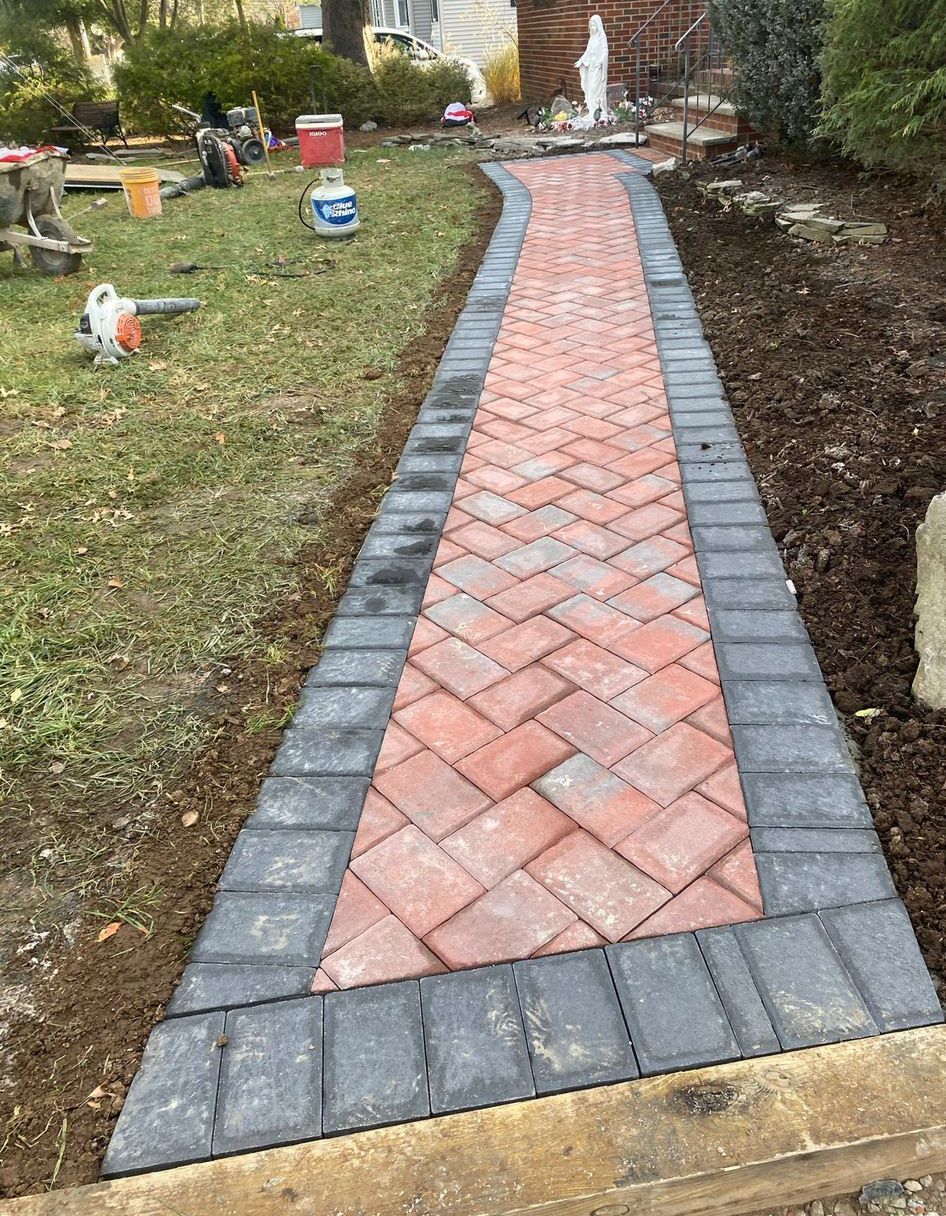 Brick garden walkway with gray border pavers leading through a yard