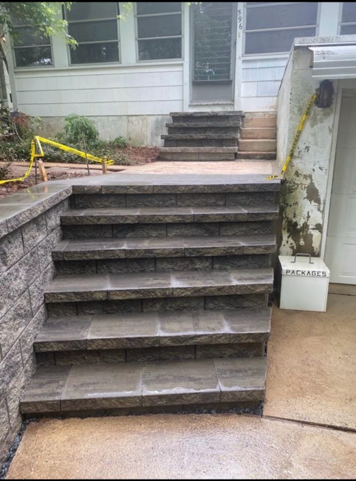 Front steps with dark stone treads leading to a house entrance, with a yellow handrail on the left.