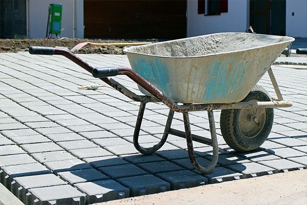 Blue wheelbarrow on a paved sidewalk at a construction site