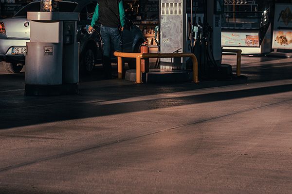 Dimly lit bus stop with benches and a trash can in the evening, casting long shadows.