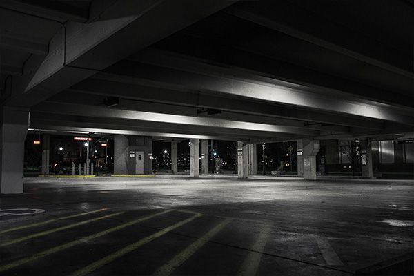 Empty dimly lit parking garage with concrete pillars and painted parking spaces