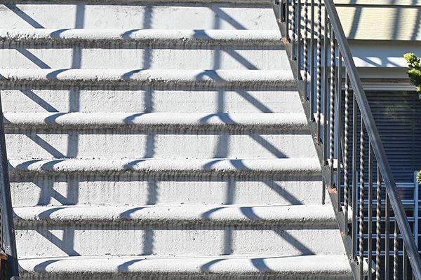 Sunlit concrete stairs with metal railings and striped shadows