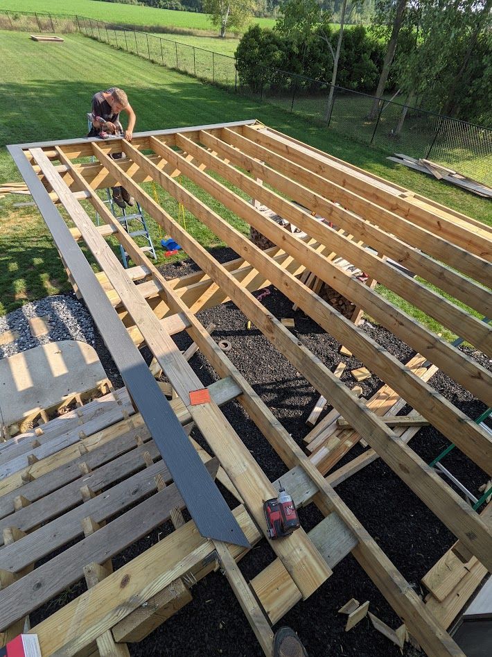 Wooden deck under construction; person working on the frame outdoors.