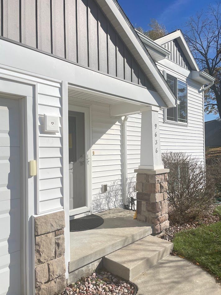 White house with porch; stone accents, steps leading up.