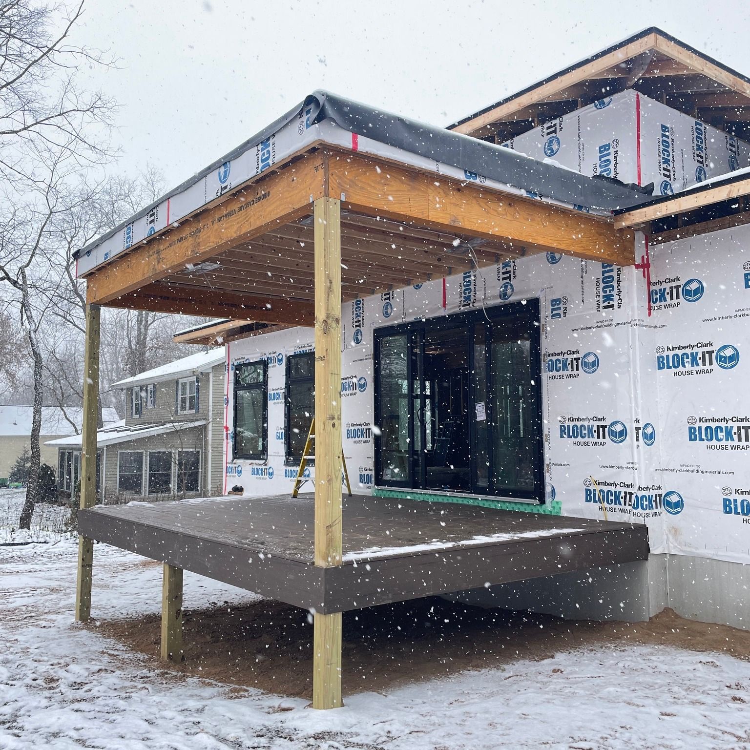 Deck construction in snowy weather with a covered porch.