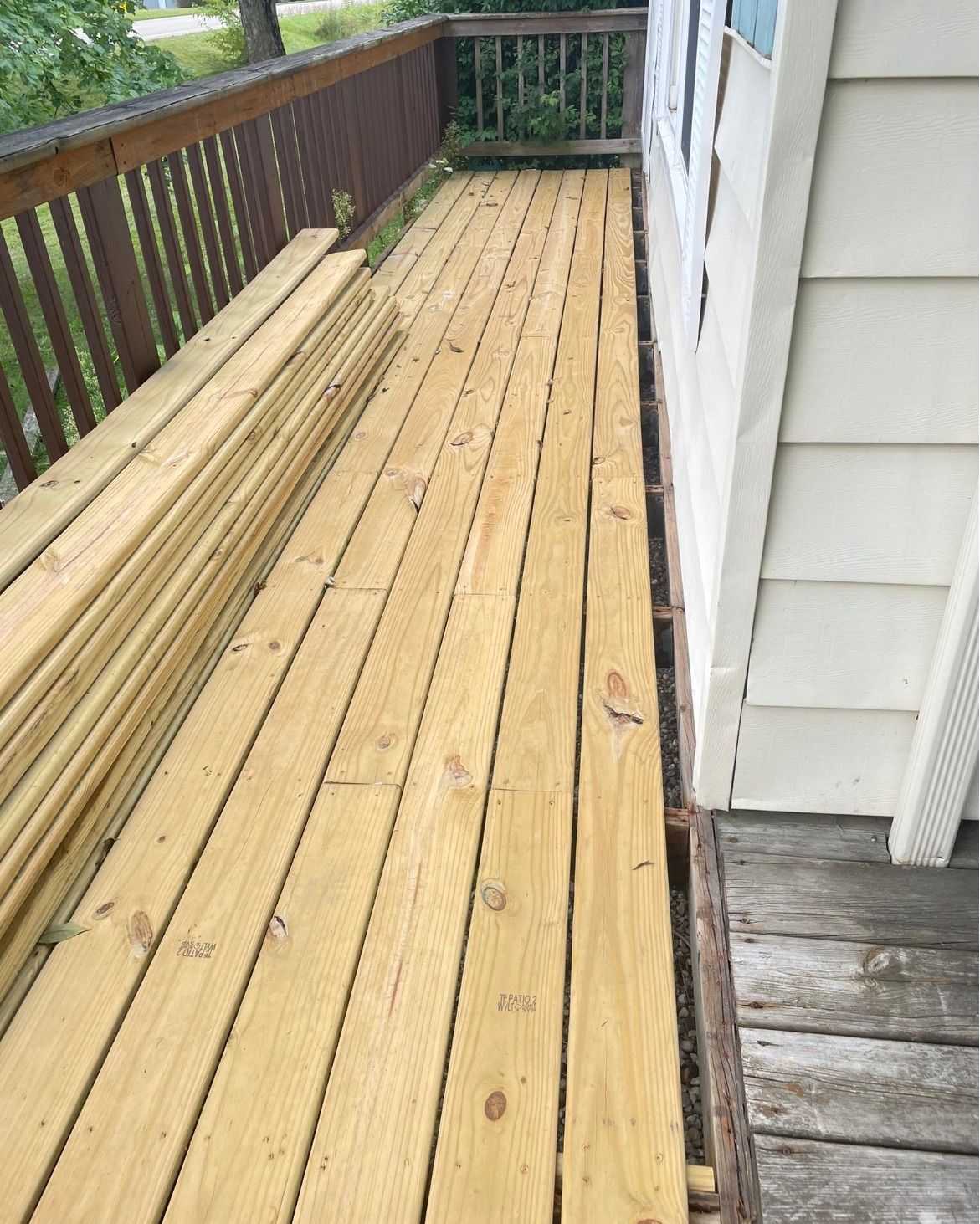 Wooden deck being renovated, new boards stacked on the side.
