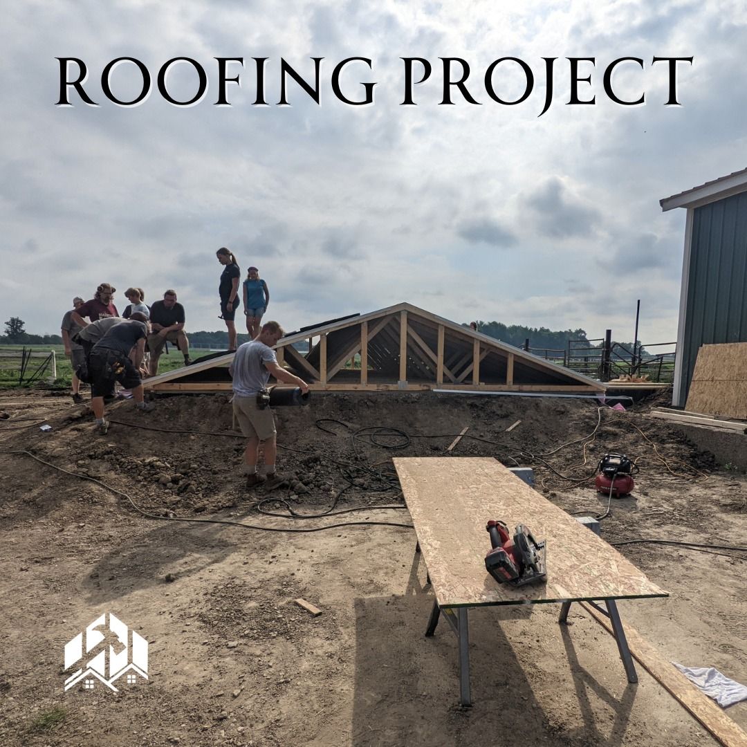 Group of people working on a roofing project outdoors, setting up a wooden truss.