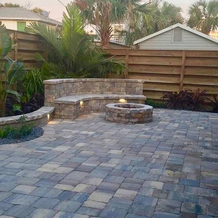 Patio with stone pavers, built-in bench, fire pit, and a wooden fence.