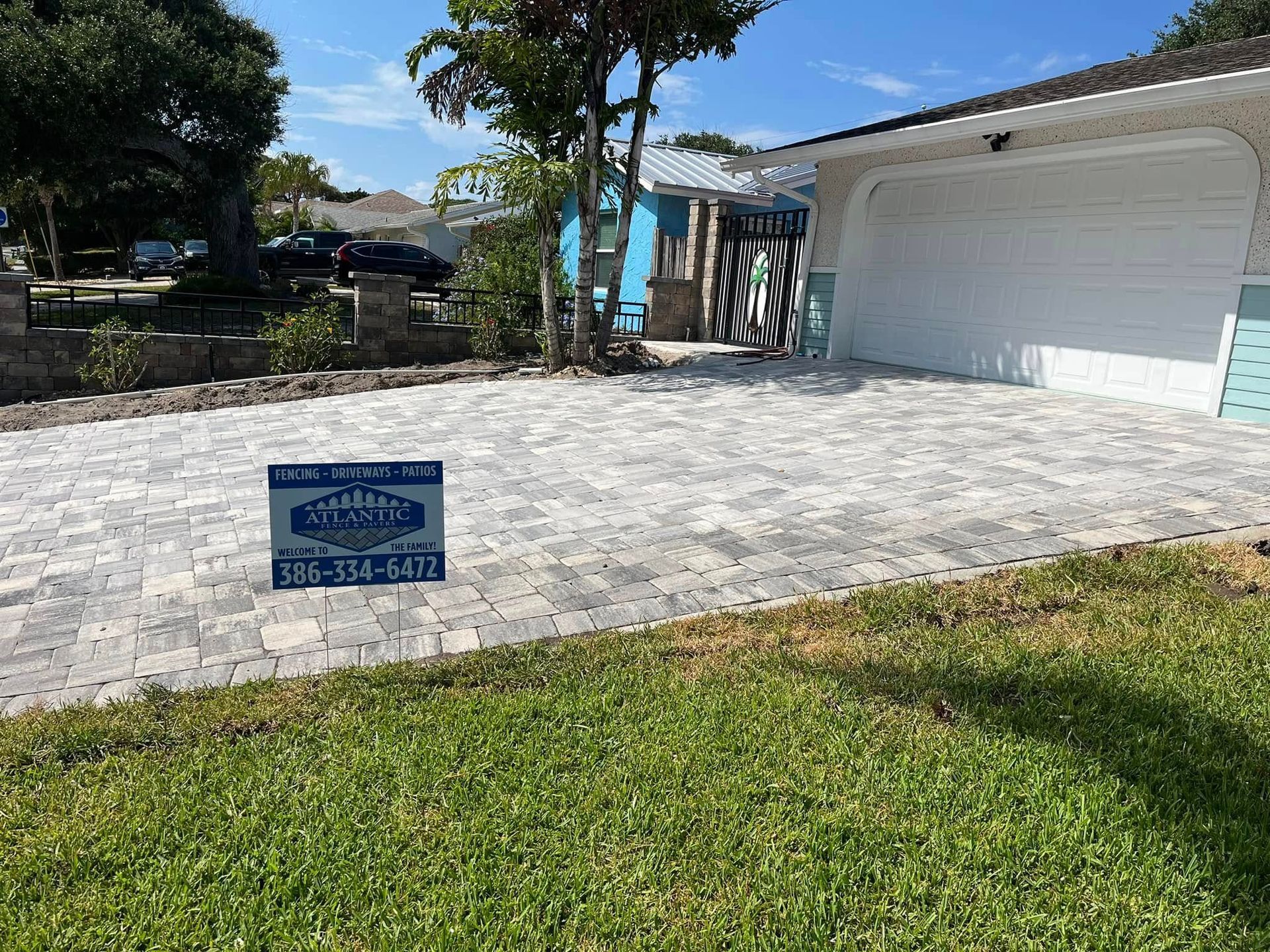 Newly paved driveway with interlocking pavers, next to a garage and lawn.